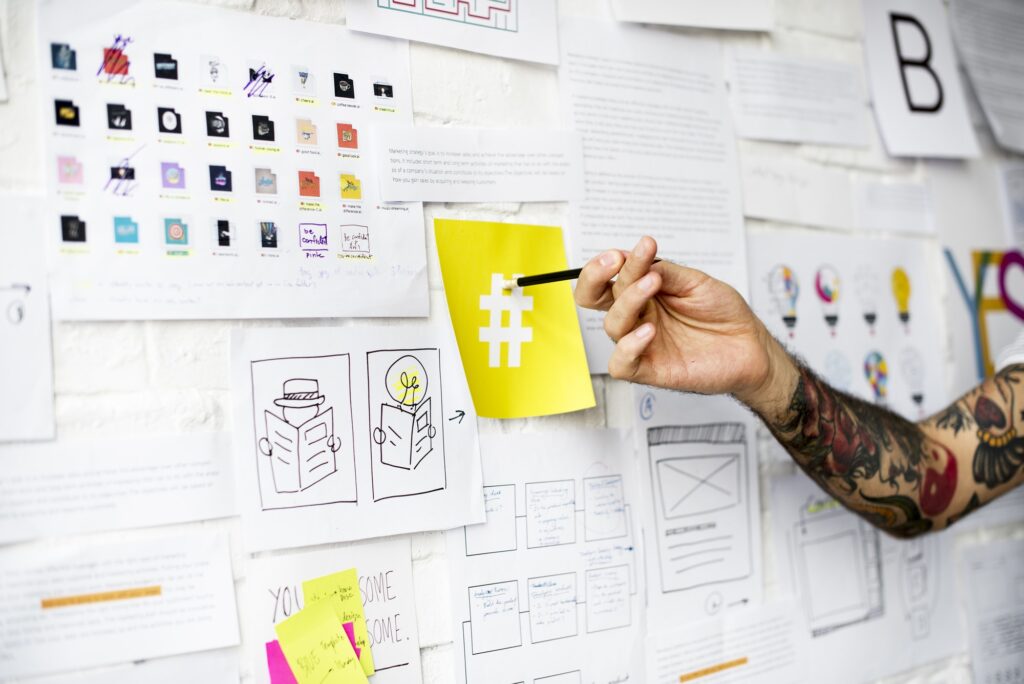 Tattoo Hand Pointing on Hashtag Sign on Yellow Note on Board Wal